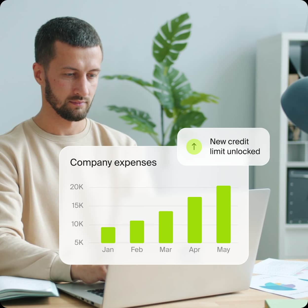 Person at laptop with company expenses chart and new credit limit unlocked notification